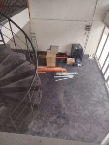 view through window looking down one floor with dirty grey carpet and electrical equipment