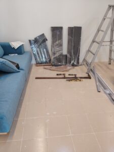 couch on left, parts for mastering console in middle and a ladder next to a wall