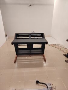 A mastering console shelf in a white room with exposed wires