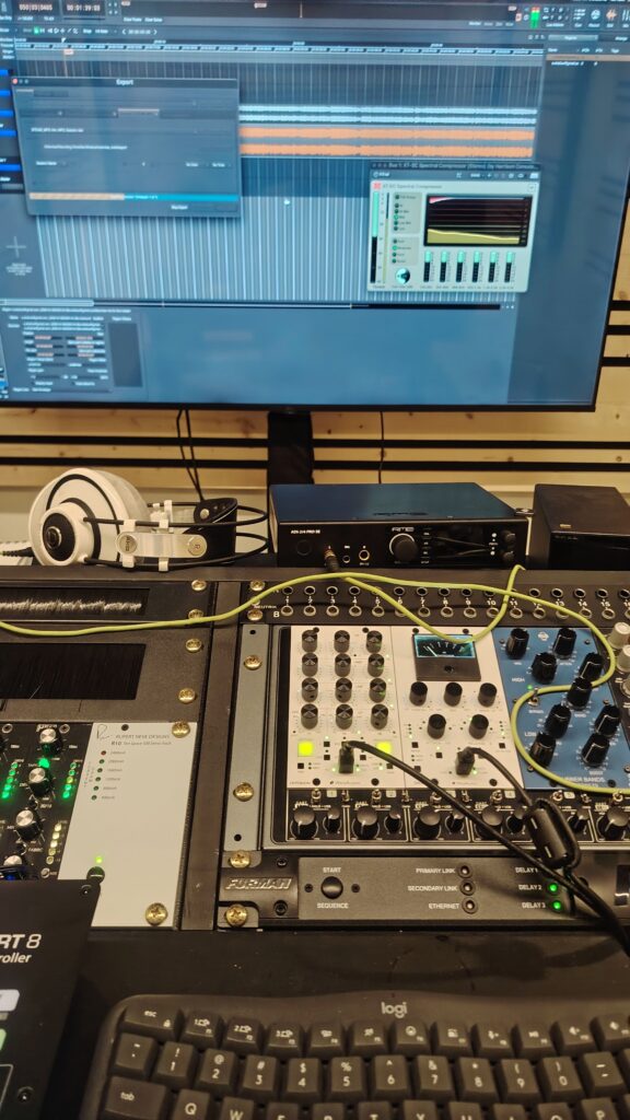 console and gear March2026 Shot of mastering rack desk with headphones on left top, some 500 series units (elysia xmax 500, wes audio hyperion and dione, IGS Rubber Bands ME - the bottom of a monitor screen is on the top half -